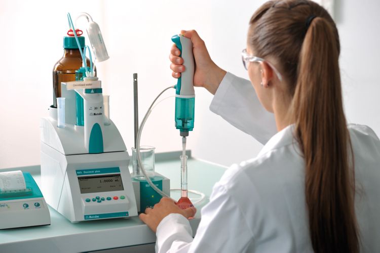 Female laboratory personnel pipetting using an 865 Dosimat plus with manual push-button cable, 63026220 Exchange Unit 20 mL, Magnetic Stirrer 801 Stirrer, Neo's printer, 61562060 Pipetting equipment for Manual Dosing Controller and 61562140 Pipetting tubi