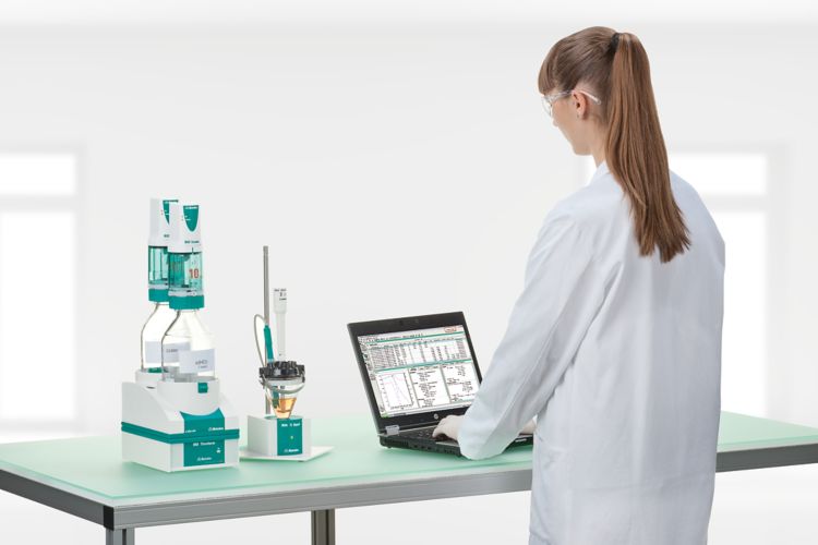 Female operator working with a titration system consisting of 859 Titrotherm, 804 Ti Stand, 62061010 Reagent Organizer, 2 x 800 Dosino and a notebook