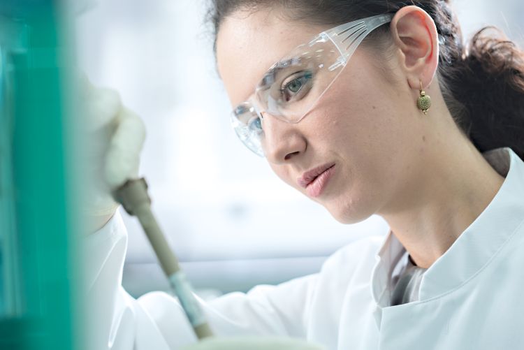 Mulher em um laboratório olhando para uma coluna de IC com óculos de proteção.