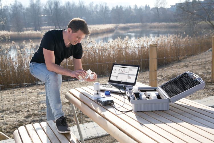 Profissional realizando análises com equipamentos e computador, em cima de uma estrutura de madeira ao ar livre