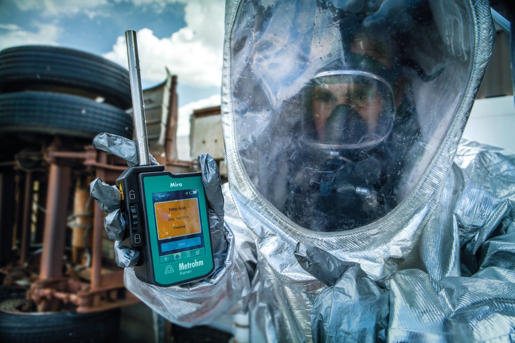 Personal de primera respuesta con un traje Hazmat que sostiene un MIRA DS con accesorio de sonda de bola de contacto para líquidos.