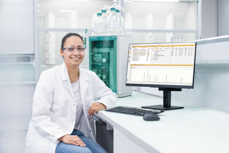 Trabajadora de laboratorio frente a una computadora que muestra el software IC MagIC Net y un sistema de cromatografía iónica Metrohm