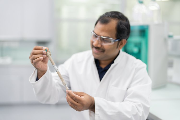 Hombre en un laboratorio mirando una columna de separación IC.