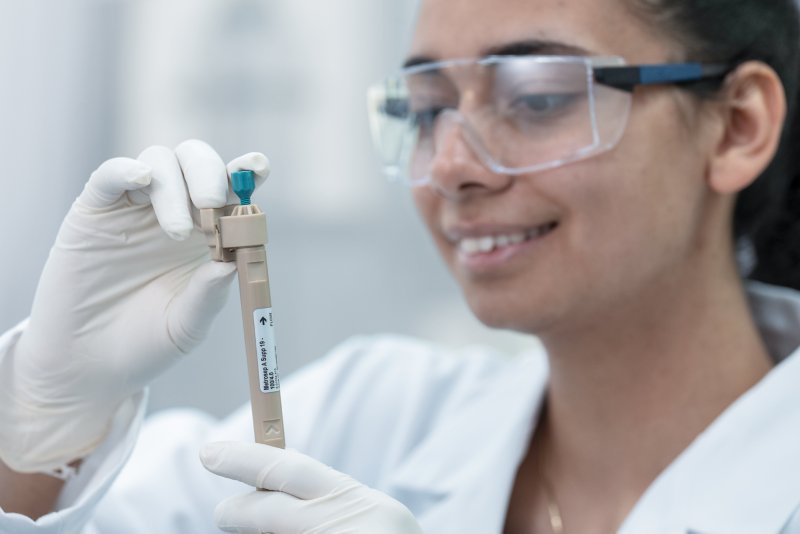Mulher em um laboratório olhando para uma coluna de IC com óculos de proteção.