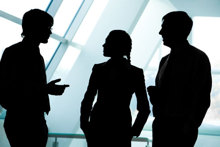 Three silhouettes of businesspeople interacting with each other in the office