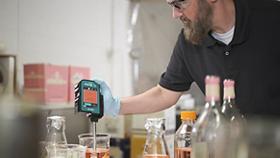 Handheld Raman, MIRA XTR DS, man analyzing an organge liquid in a sample vessel