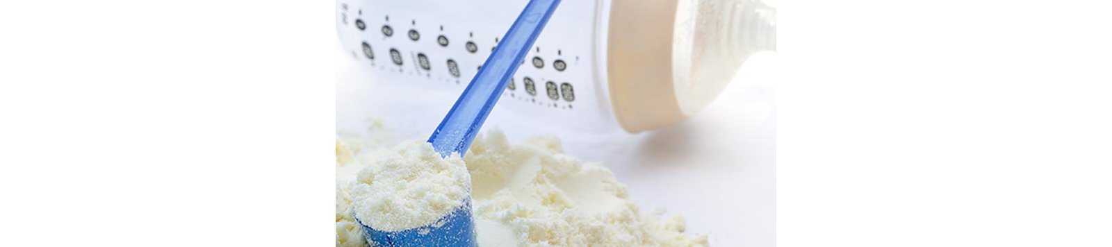 A close-up shot of baby milk formula with a plastic measuring spoon and bottle.